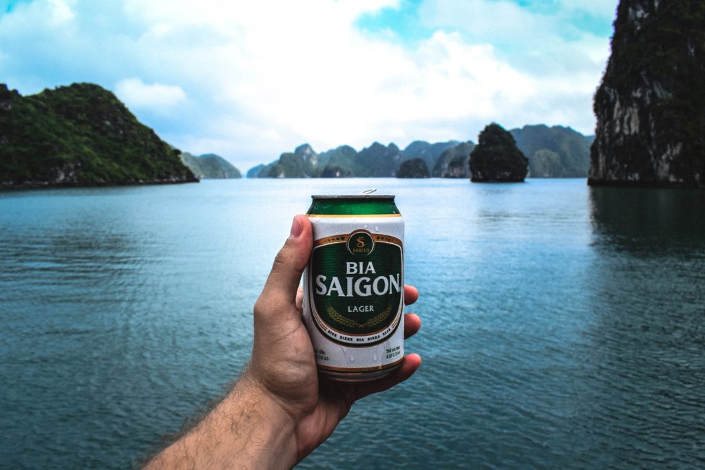 Man holding Bia Saigon can in front of Halong Bay