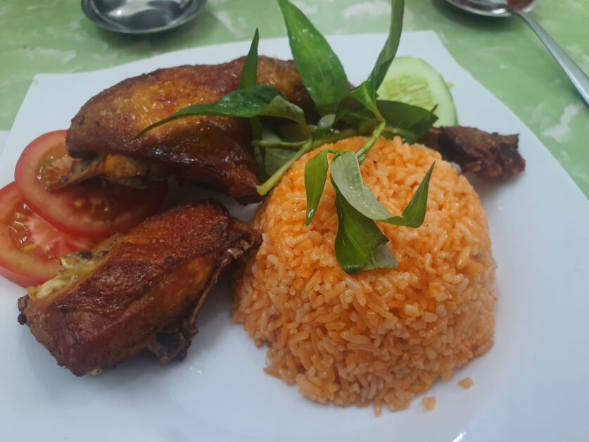 Cơm Gà Xối Mỡ Su Su chicken thigh platter with orange fried rice, cucumber and tomatoes