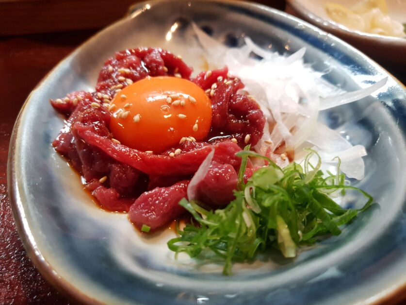 horse tartare with raw egg yolk on top and raw onions