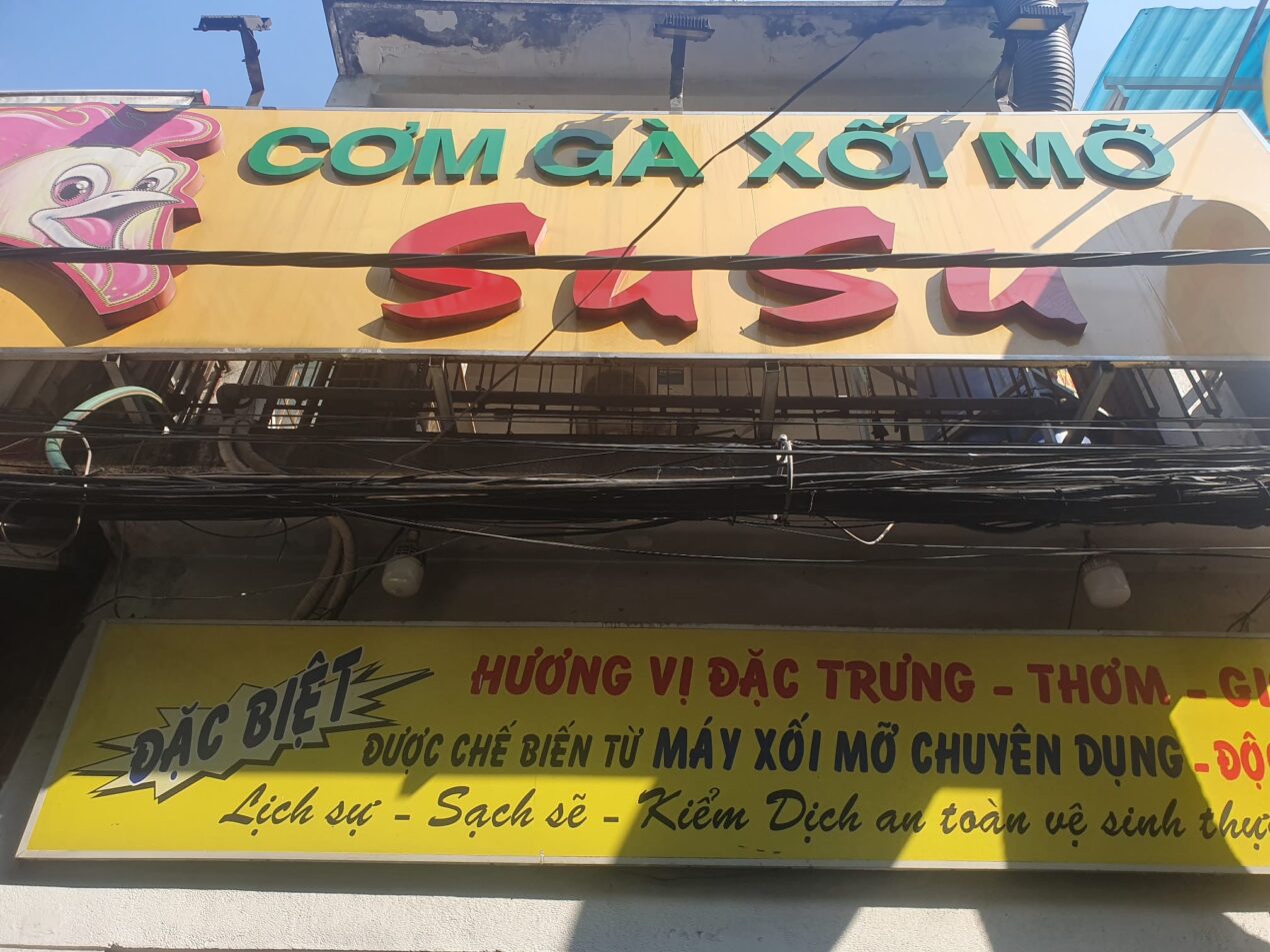 Cơm Gà Xối Mỡ Su Su yellow sign with green and red lettering