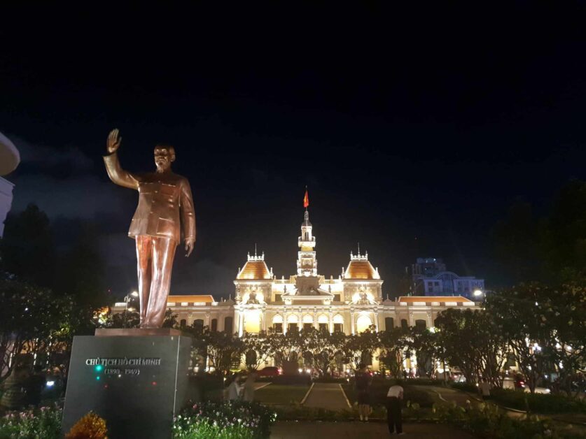 Ho Chi Minh statue with city hall in background at night