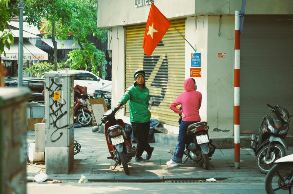 Grab driver drinking water next to Vietnamese flag